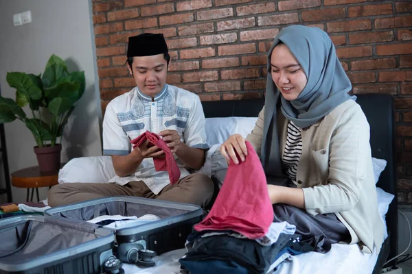 Asiático musulmán pareja preparar ropa y maleta antes de volver a casa —  Fotos de Stock