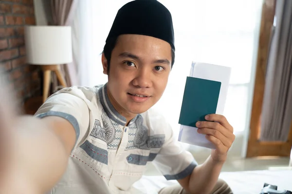 Pria Muslim selfie menggunakan kamera ponsel ketika memegang paspor — Stok Foto