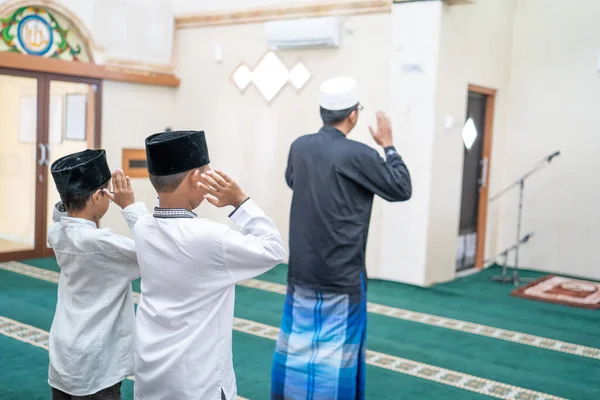 Отец и сын молятся вместе в мечети — стоковое фото