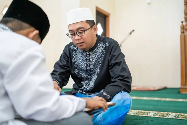 Uczy muzułmańskie dziecko czytać Koran — Zdjęcie stockowe