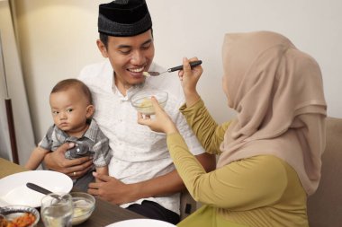 Kocasına yemek servisi yapan tesettürlü kadın.