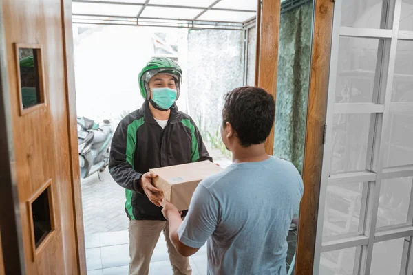 Entrega mensajero desgaste mascarillas mientras entrega paquete — Foto de Stock