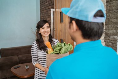 Gülümseyen kadın eve market teslimatı alıyor.