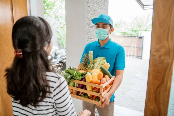 Homem entrega usar máscaras faciais durante a entrega de alimentos — Fotografia de Stock