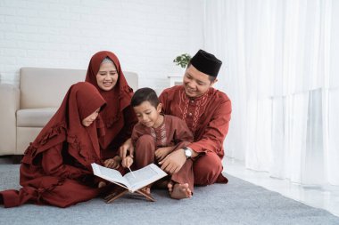 Asyalı aile boş zamanlarında birlikte Kur 'an İncili öğrenir.