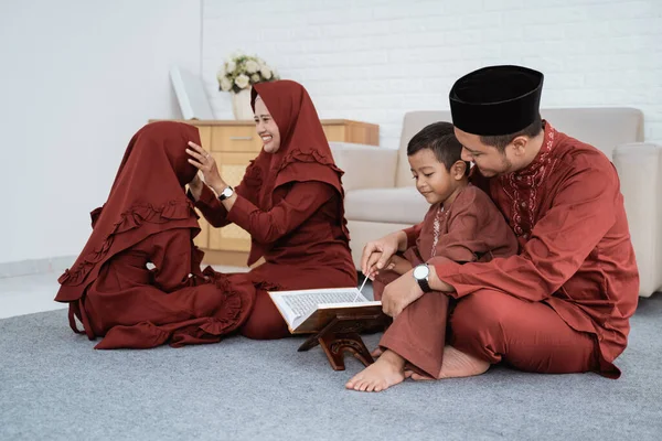 Familia musulmana aprenden juntos la biblia del Corán cuando tienen tiempo libre — Foto de Stock