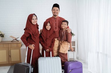 Kızı ve oğlu olan Asyalı bir aile bavullarını taşımaya hazır.