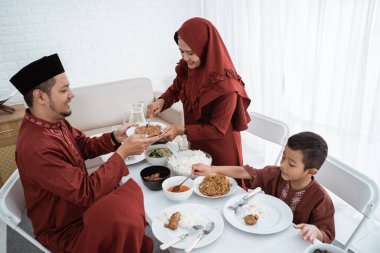 Müslüman aile kahvaltıda yemek için oturur.