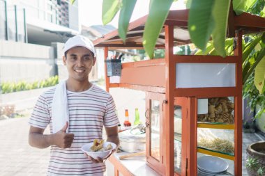 Adam bakso satıyor ve yemek arabalarını itiyor.