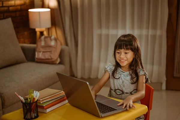 Χαρούμενο κοριτσάκι κάνει την εργασία χρησιμοποιώντας το lap-top — Φωτογραφία Αρχείου