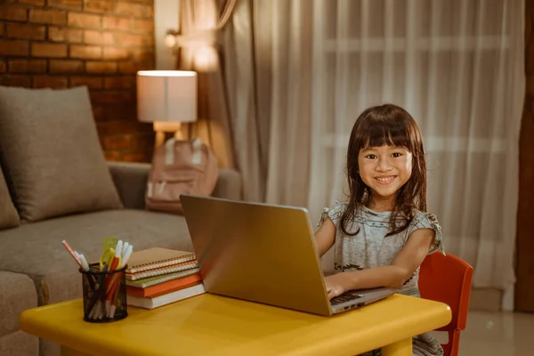 Χαρούμενο κοριτσάκι κάνει την εργασία χρησιμοποιώντας το lap-top — Φωτογραφία Αρχείου