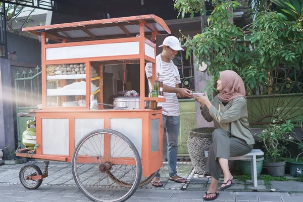 Street food vendor handing a bowl of bakso — Stock Photo, Image