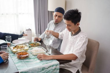 Müslüman baba ve oğul birlikte yemek yiyorlar.