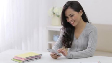 Mutlu öğrenci akıllı telefon kullanarak evde çalışıyor.