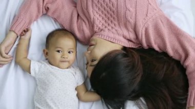 Genç anne bebeğiyle yatakta yatıyor.