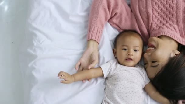 Joven madre acostada con su bebé en la cama — Vídeo de stock