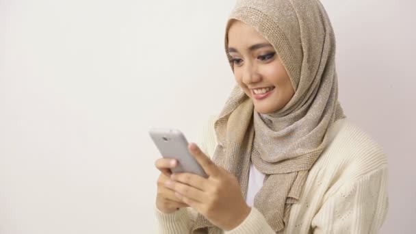 Portré egy mosolygós, gyönyörű muszlim nőről, aki sms-ezik az sms-ével. — Stock videók