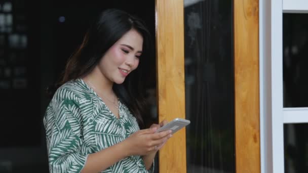 Frau benutzt Handy vor ihrem Haus — Stockvideo