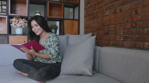 Mujer escribiendo libro mientras está sentada en un sofá — Vídeos de Stock