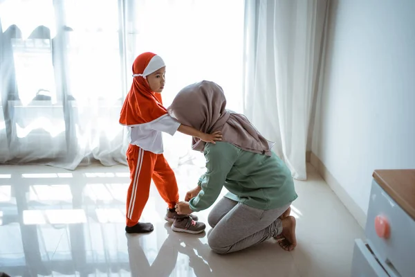 Ibu muslim membantu anak perempuan untuk mengenakan sepatu — Stok Foto
