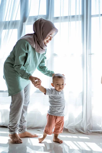 Mutter hilft ihrem Sohn den ersten Schritt zu gehen — Stockfoto