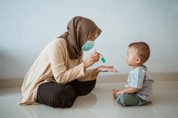 Muzułmanka stosująca środek do dezynfekcji rąk na syna — Zdjęcie stockowe
