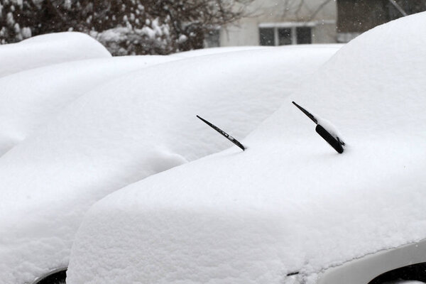 Winter. Cars covered with snow. Uncleaned streets with heavy snowdrifts after snowfall in the city. Puddles. icy roads. icy streets