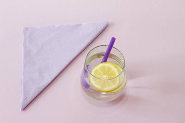 Bir bardak su ve limon. Bardak saf su ve taze organik limon mor arka plan üzerinde izole. Detoks ve sağlıklı gıda kavramı. Artırmak metabolizma kavramı. 