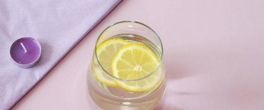 Bir bardak su ve limon. Bardak saf su ve taze organik limon mor arka plan üzerinde izole. Detoks ve sağlıklı gıda kavramı. Artırmak metabolizma kavramı. 