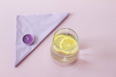Bir bardak su ve limon. Bardak saf su ve taze organik limon mor arka plan üzerinde izole. Detoks ve sağlıklı gıda kavramı. Artırmak metabolizma kavramı. 
