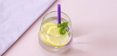Bir bardak su, limon ve nane. Bir bardak saf su ve taze organik limon ve nane mor arka plan üzerinde izole. Detoks ve sağlıklı gıda kavramı