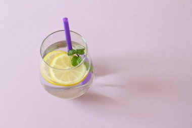 Bir bardak su, limon ve nane. Bir bardak saf su ve taze organik limon ve nane mor arka plan üzerinde izole. Detoks ve sağlıklı gıda kavramı