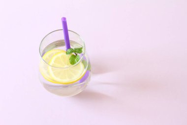 Bir bardak su, limon ve nane. Bir bardak saf su ve taze organik limon ve nane mor arka plan üzerinde izole. Detoks ve sağlıklı gıda kavramı