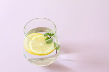 Bir bardak su, limon ve nane. Bir bardak saf su ve taze organik limon ve nane mor arka plan üzerinde izole. Detoks ve sağlıklı gıda kavramı
