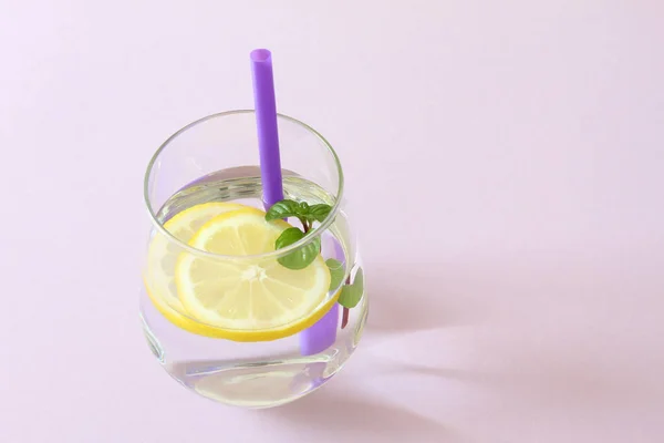 レモン ミントのガラス ガラスの純粋な水と新鮮なオーガニック レモンとミントの紫色の背景に分離されました デトックスと健康食品のコンセプト — ストック写真