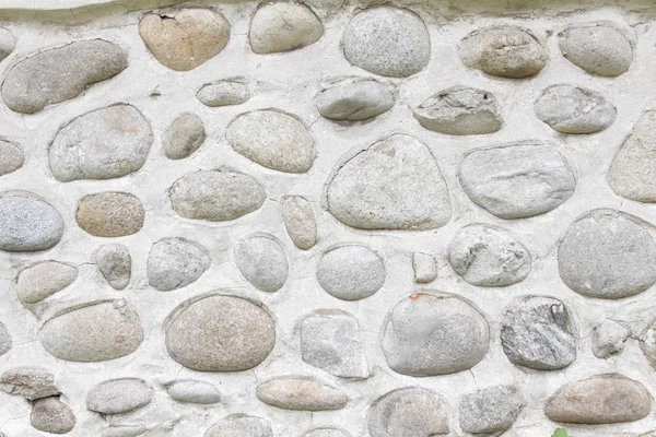 Rock wall of natural river stones. Round stones wall background. River round Stones pattern. Stones texture. River rocks background.