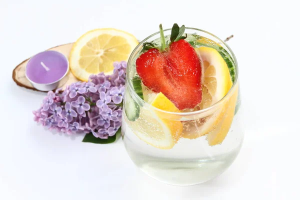 Detox flavored water with lemon, cucumber and  strawberry on white background with lilac and wood decoration. Healthy food concept.  Refreshing summer homemade cocktail. Copy space. No sharpen