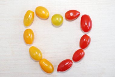 Sarı ve kırmızı domatesler, kalplerinde ahşap bir zemin üzerinde.