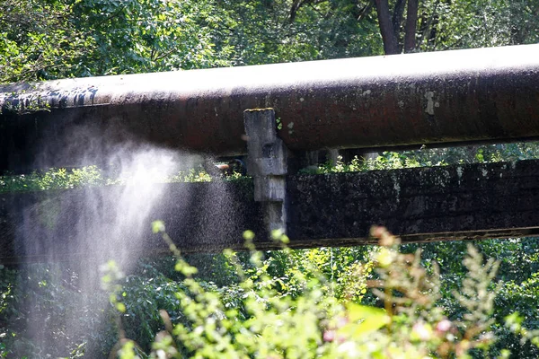 Tubos oxidados y agrietados rocían agua en la naturaleza. Red de suministro de agua — Foto de Stock