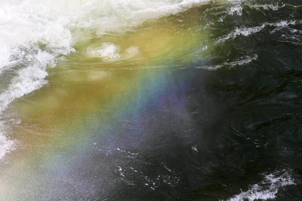 Rainbow above heavy water of a dam
