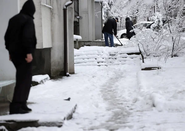 Mensen lopen op ongereinigd trottoir, glad en ijzig trottoir — Stockfoto