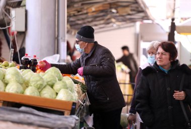 COVID-19 'dan korunmak için maske takan insanlar, 17 Mart 2020' de Bulgaristan 'ın Sofya kentindeki pazarda sebze ve meyve alışverişi yapıyorlar..