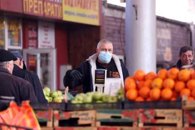 COVID-19 'dan korunmak için maske takan insanlar, 17 Mart 2020' de Bulgaristan 'ın Sofya kentindeki pazarda sebze ve meyve alışverişi yapıyorlar..
