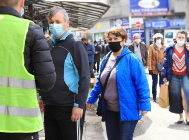 Bulgaristan 'ın Sofya kentindeki bir pazar yerine girmek için 04 / 14 / 2020 tarihli kuyrukta, Coronavirus COVID-19 hastalığının önlenmesi için maske takan insanların sıkı denetimi ve dezenfekte edilmesiyle,.