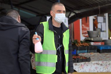 Bulgaristan 'ın Sofya kentinde, koronavirüs COVID-19 hastalığının yayılması ve korunmasına yardım eden kamuya açık bir yerde maske ve dezenfektanla çalışan belediye çalışanı