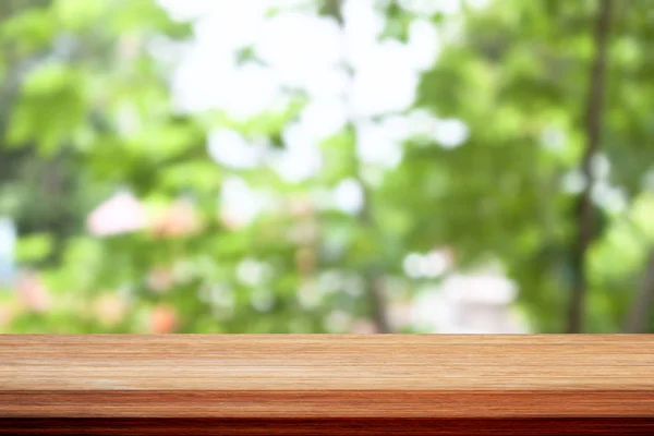 Holz Tischplatte auf Bokeh grünen Blättern Hintergrund — Stockfoto