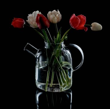 Siyah arka planda çiçekli cam çaydanlık.