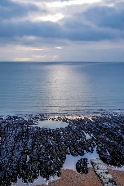 Gelber Kiesstrand Eine Reihe Schwarzer Strukturierter Felsformationen Wasserrand Ein Kreisförmiger — Stockfoto