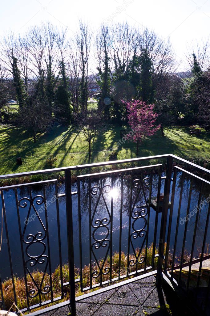 view from a small balcony over a pond and garden