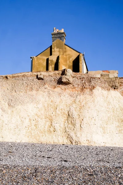 Erosión, Lado de una casa adosada sentada en el borde de una cha blanca —  Fotos de Stock